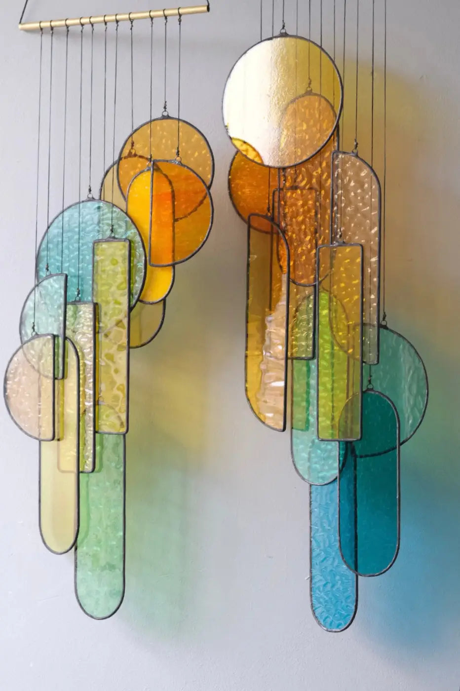 A vibrant autumn 2 stained glass hanging sculpture featuring amber teal green and gold circular and rectangular pieces