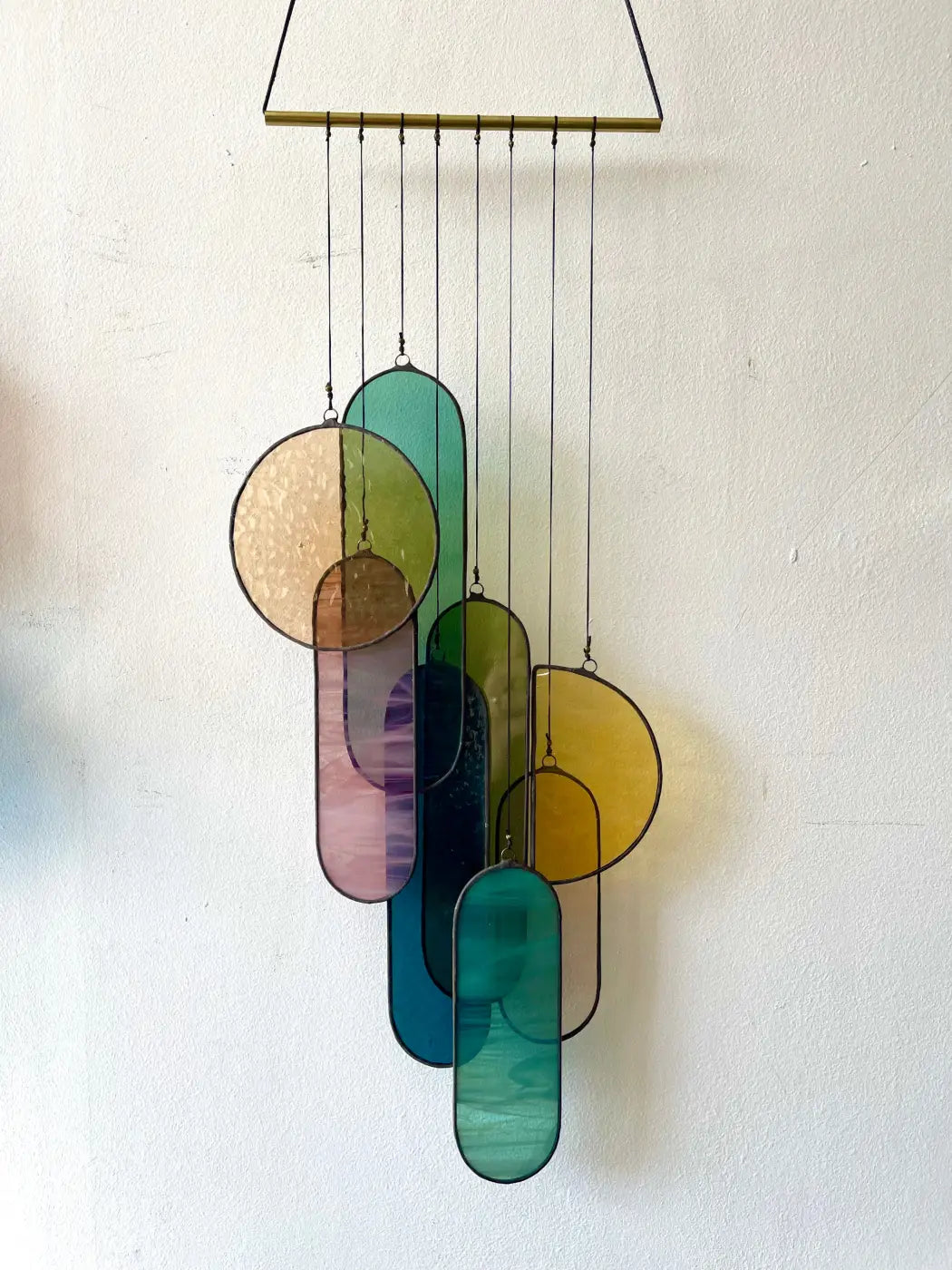 Barra stained glass art colorful wind chime with teal amber purple and gold oval and circular pieces hanging from brass bar