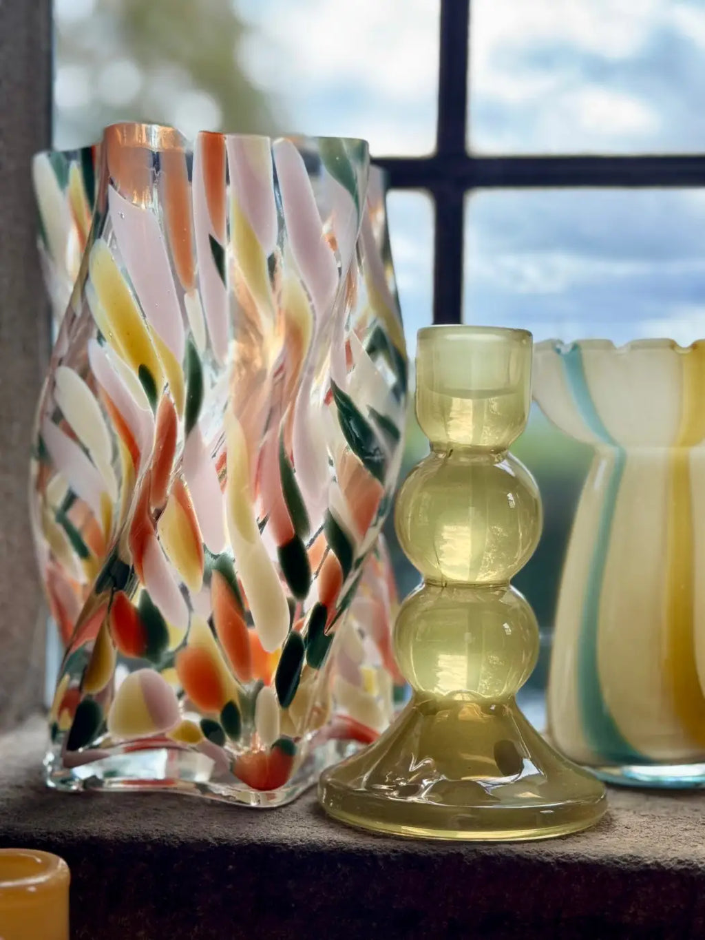 Bobbin glass candle holder featuring a translucent wavy glass vase with pastel pink orange and green swirls