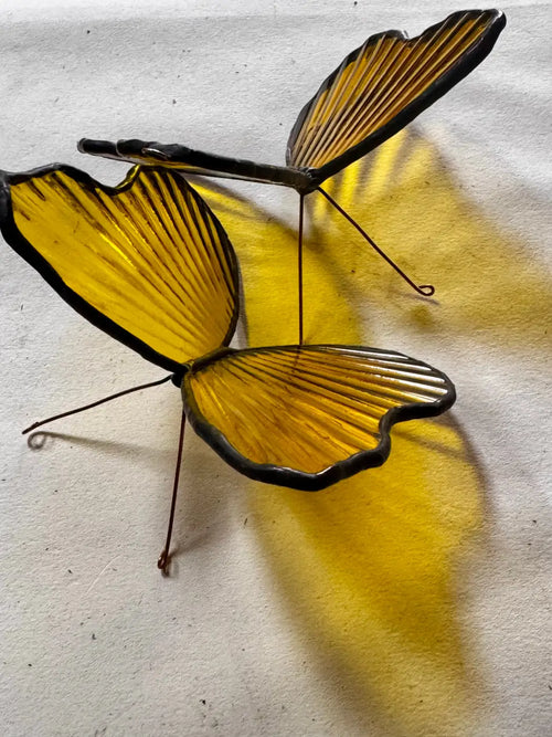 Brimstone butterfly decorative sculpture featuring yellow stained glass wings with black metal outlines and wire legs