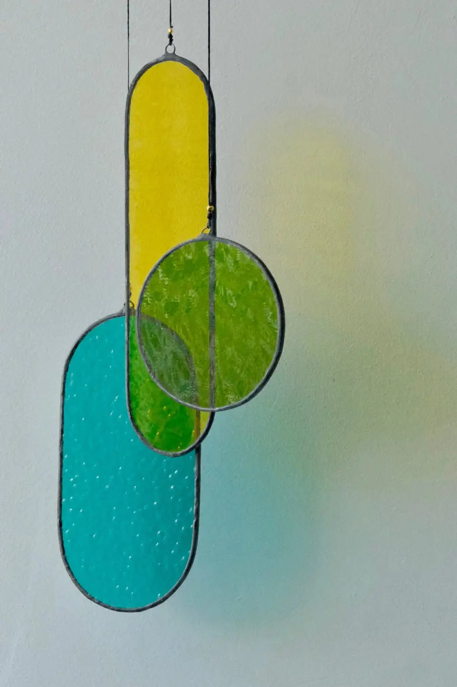 Circa 2 stained glass art panel with vibrant yellow oval, textured green circle, and turquoise oval in dark metal frame