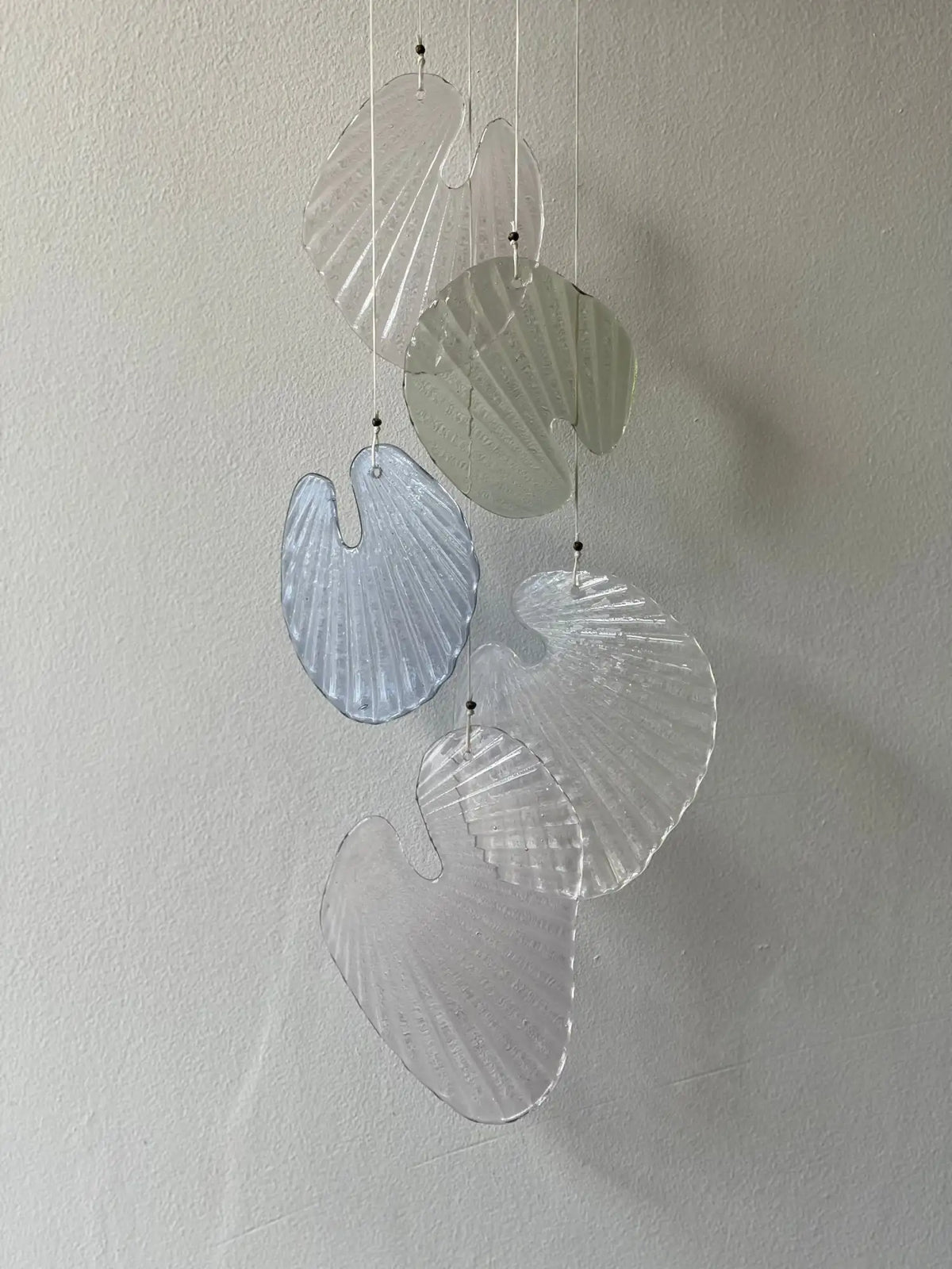 Clear and light blue glass seashell wind chime with ribbed texture.