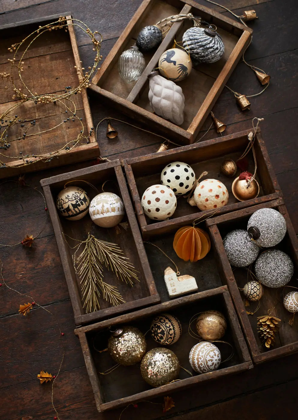 A collection of hand painted paper mache baubles in metallic gold silver and white with intricate patterns and finishes