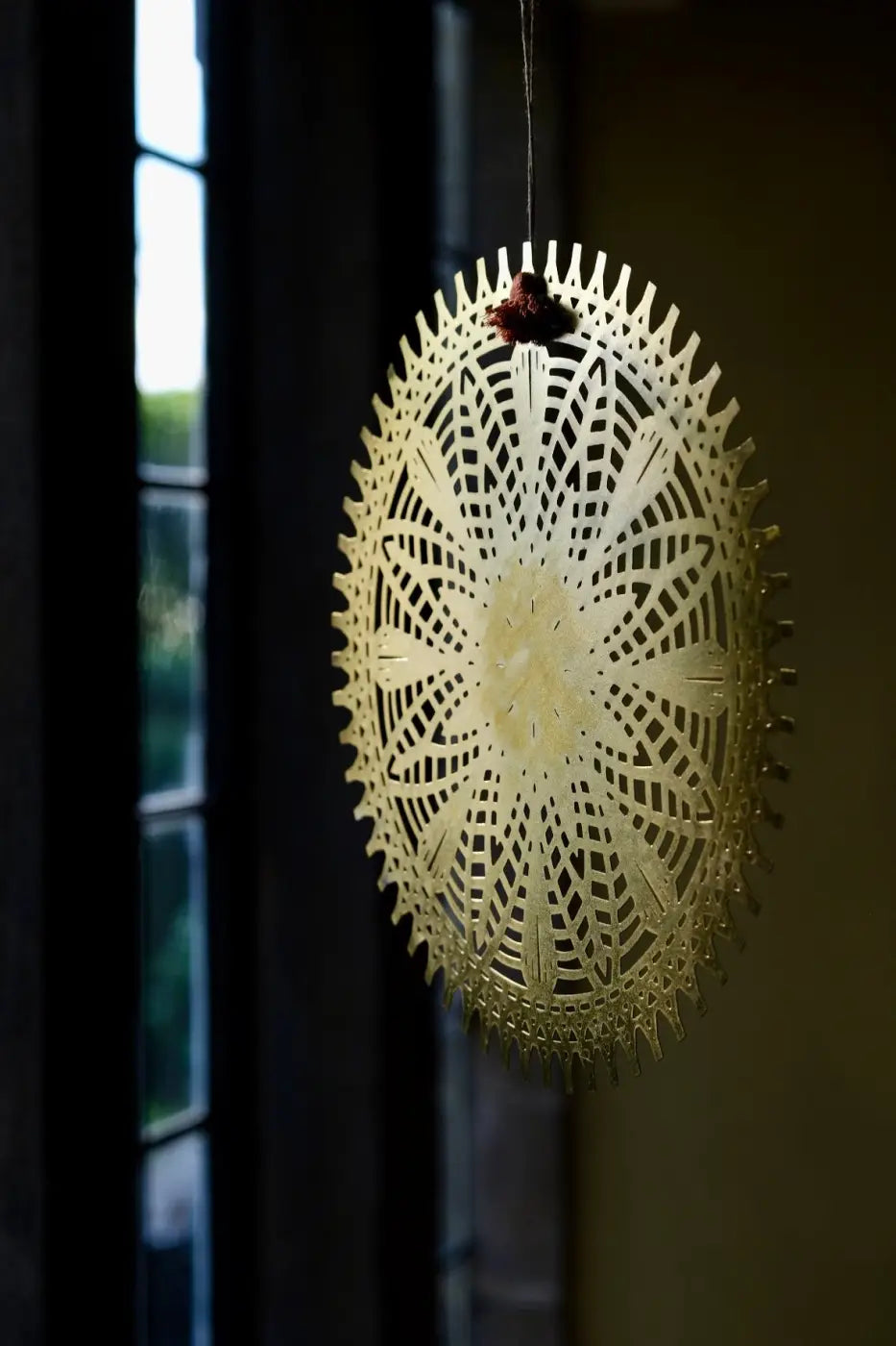 Handmade iron decoration with delicate golden-yellow circular lace-like pattern and pointed edges hanging ornament