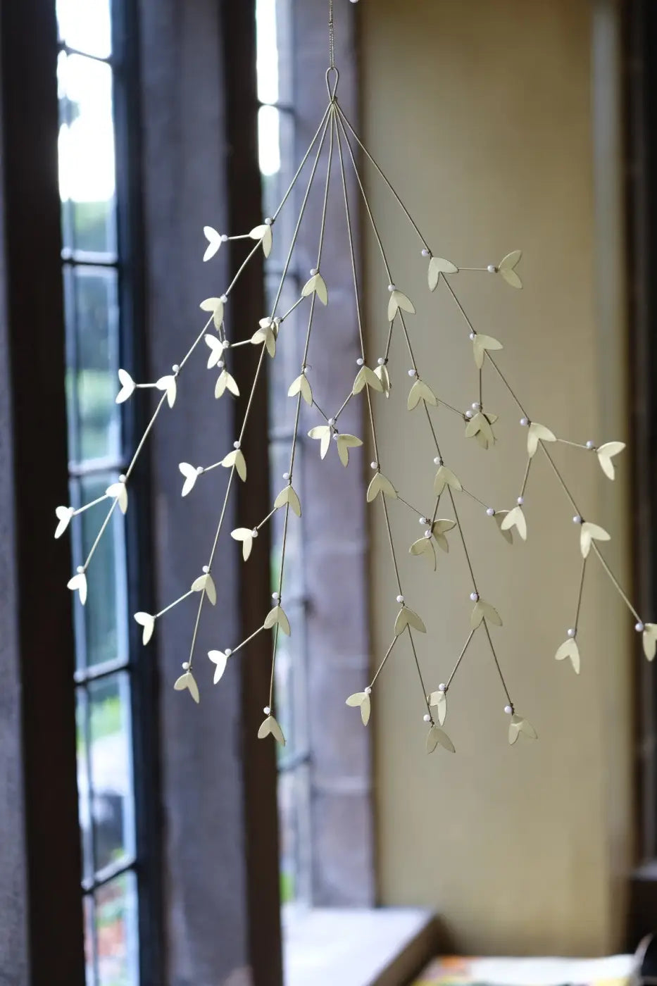 Handmade iron mistletoe ornament with delicate slender branches and small white leaf-like charms in metallic finish