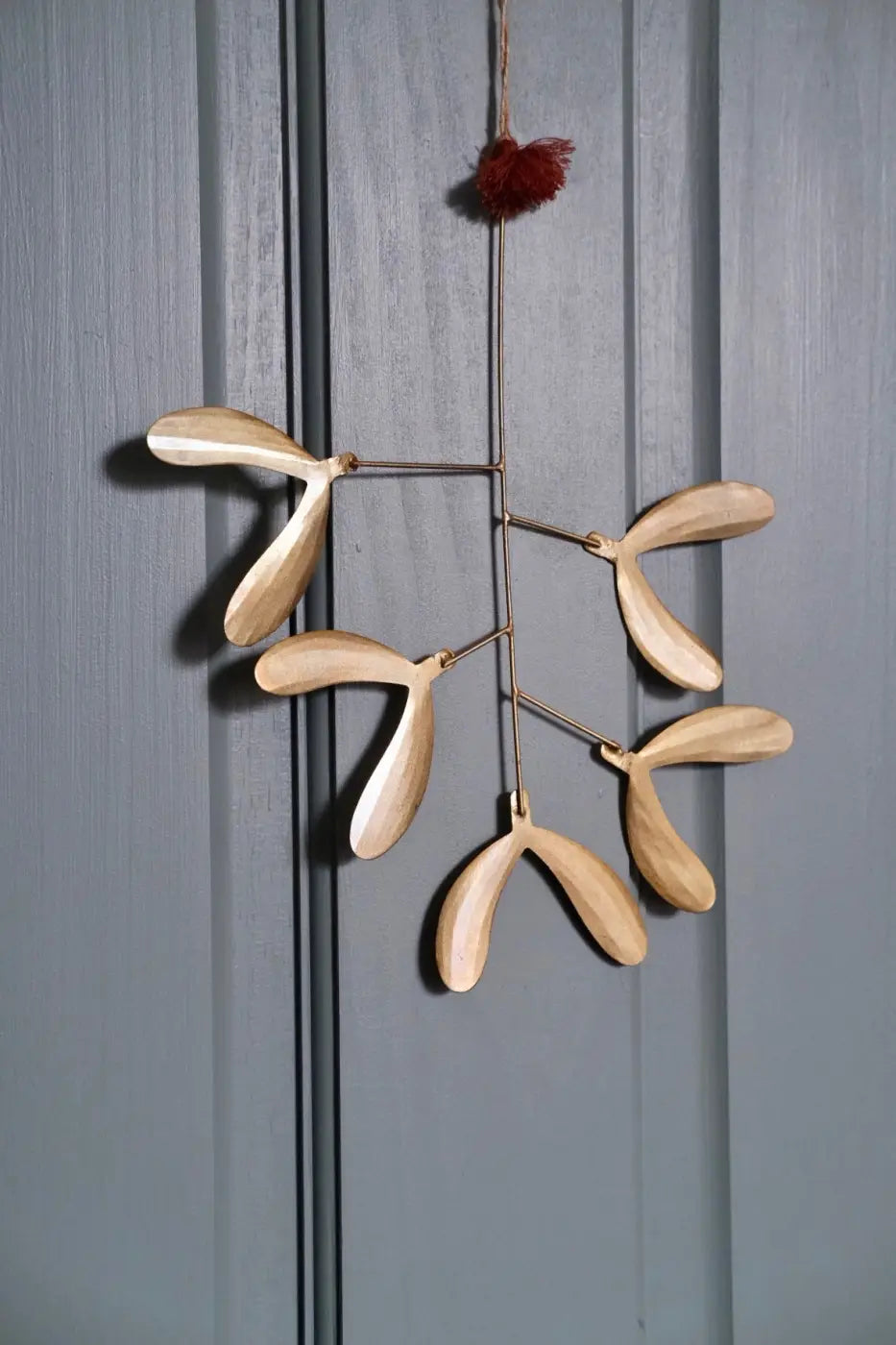 Handmade iron mistletoe small light-colored wooden mobile with a delicate design and a red pom-pom top