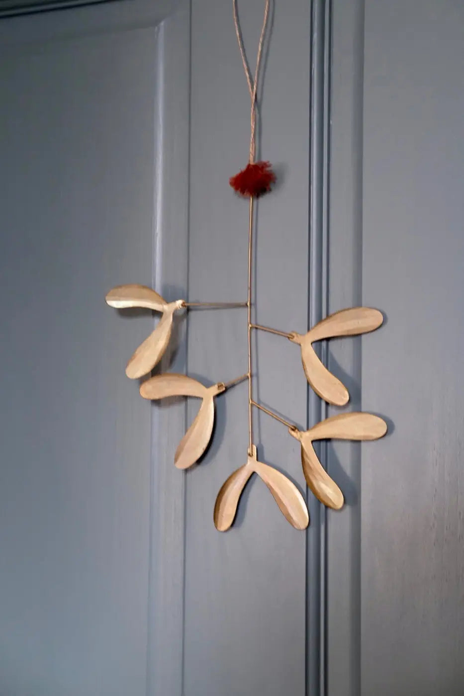Handmade iron mistletoe ornament with delicate light wood detailing and a red pom-pom on top small size