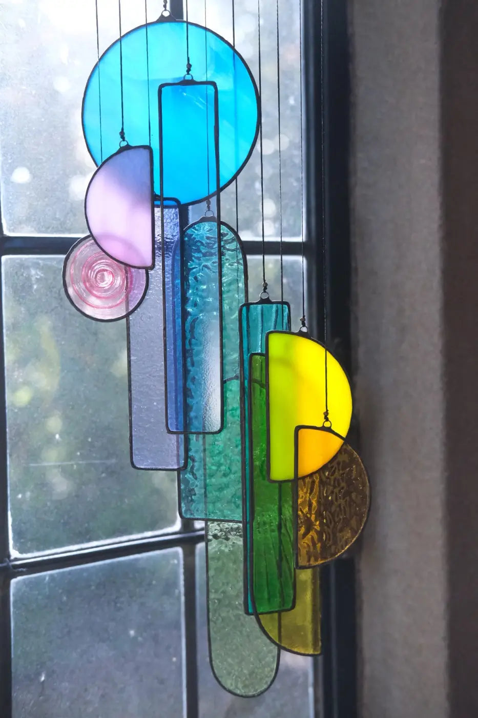 Lawrence 1 stained glass sun catcher artwork featuring colorful circular and rectangular pieces in blue pink green yellow amber