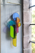 Lawrence 2 stained glass sun catcher artwork features a vibrant geometric wind chime with colorful translucent panels