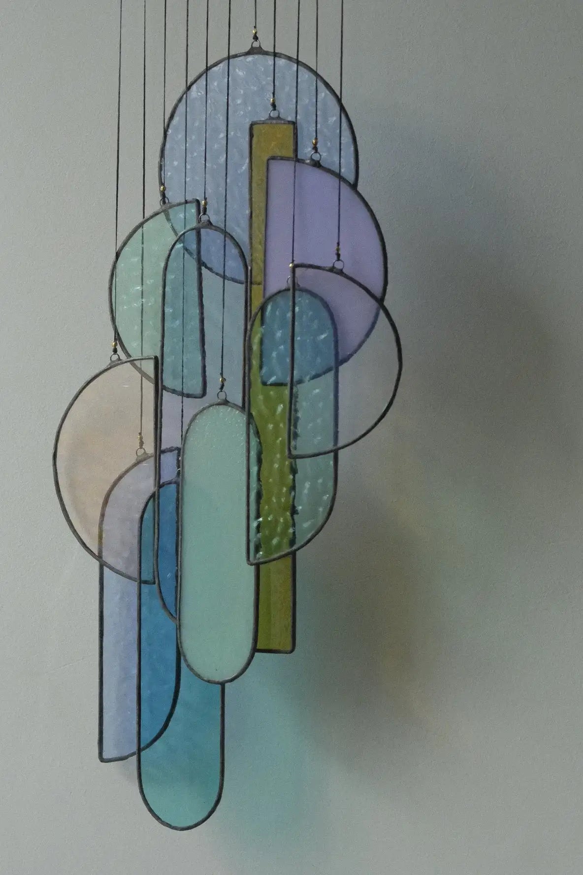 A modern stained glass chandelier featuring overlapping translucent circles and rectangles in soft pastel hues of blue, lavender, mint green, and yellow.