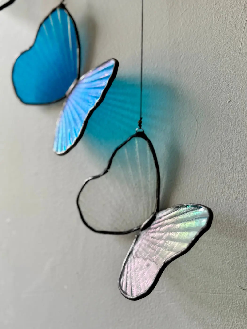 Morpho butterfly decorative sculpture featuring blue and iridescent stained glass butterflies with black outlines hanging from a string