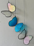 Decorative glass butterflies hanging against a plain wall