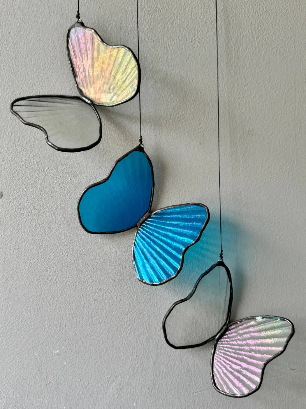 Decorative glass butterflies hanging against a plain wall