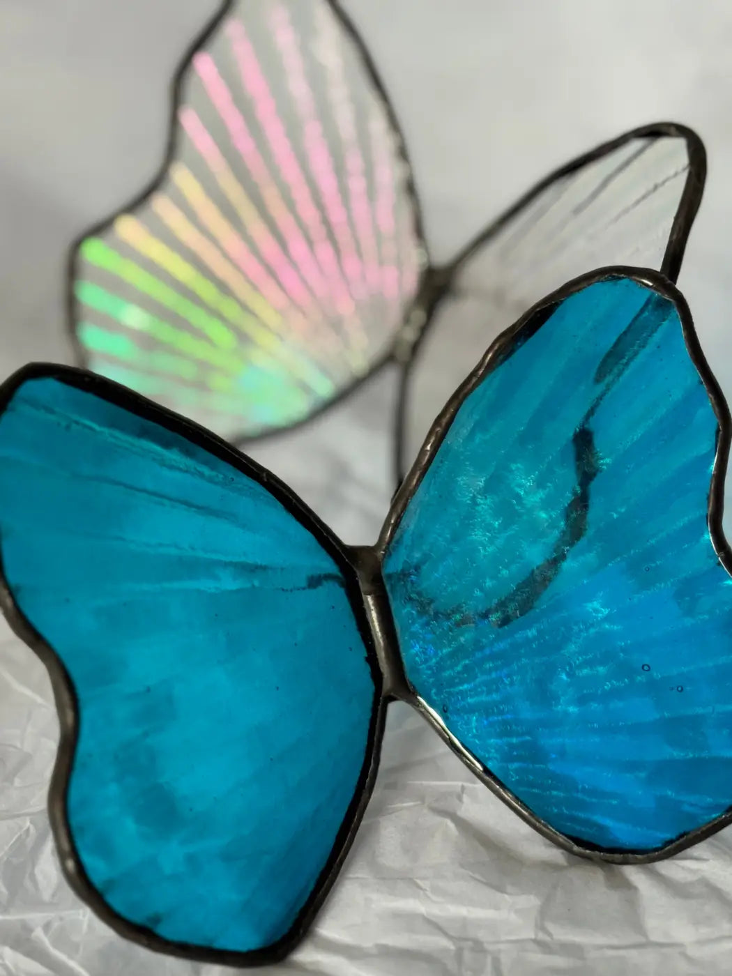 Stained glass morpho butterfly decorative sculpture with vibrant blue wings and an iridescent wing in the background