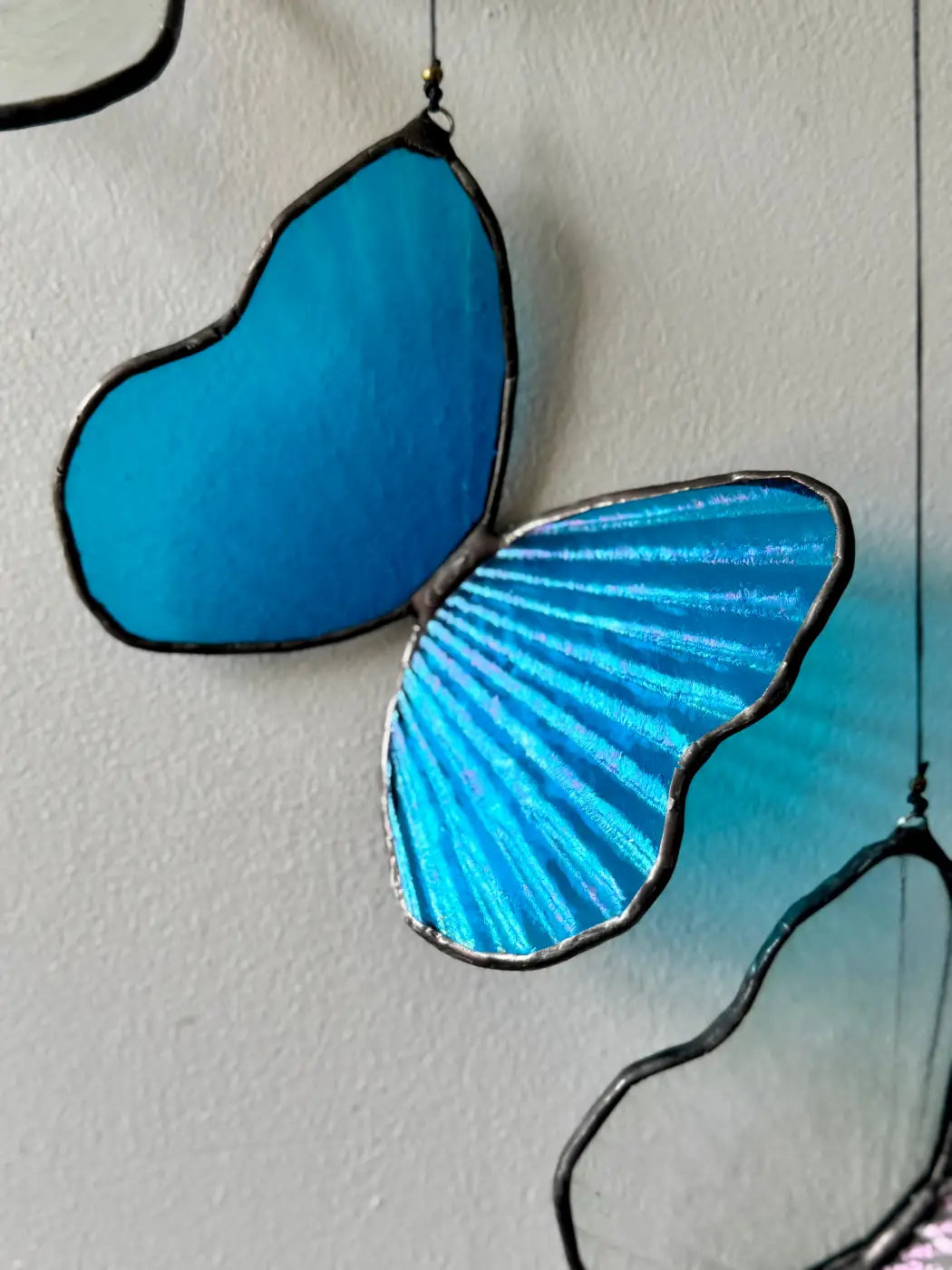 Morpho butterfly decorative sculpture with vibrant blue stained glass wings and dark metal frame featuring radial patterns