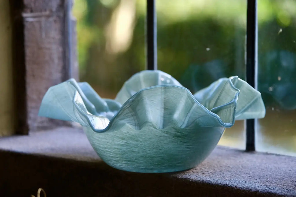 Translucent light blue glass ruffle bowl with flowing rim, elegant decorative centerpiece for home or dining table