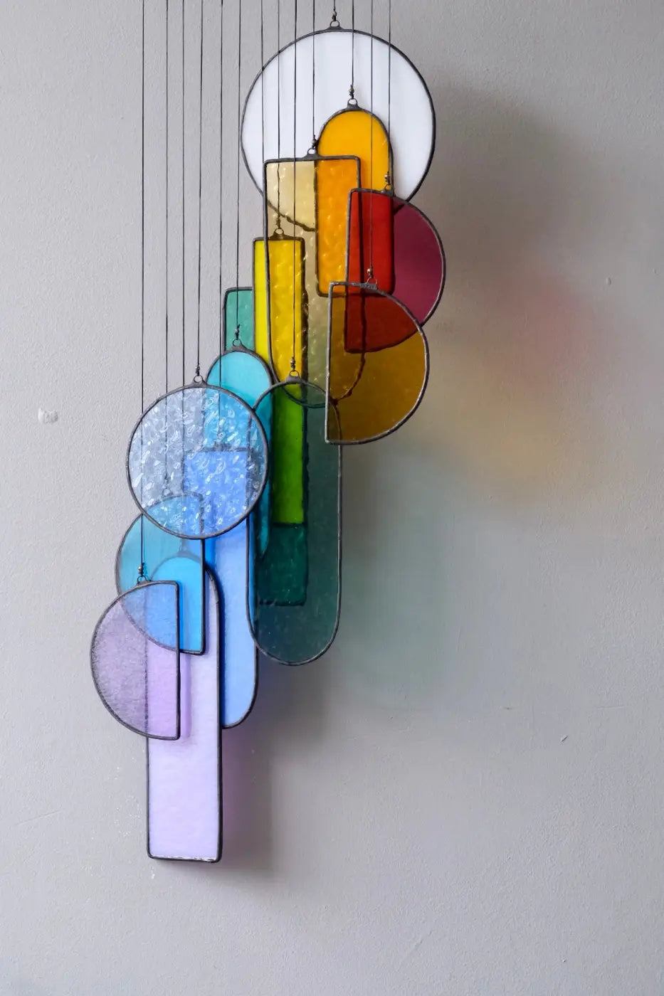 A colorful sagrada stained glass hanging art mobile with geometric shapes in yellow red blue green and purple