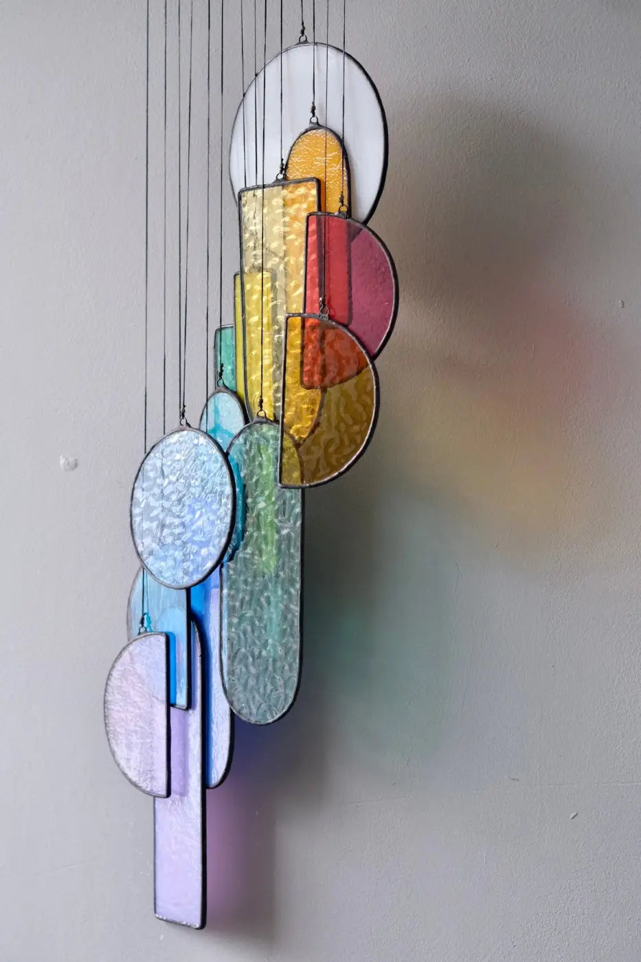 Sagrada stained glass hanging art with colorful circular and rectangular panels in white yellow red blue green and purple