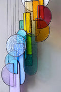 A vibrant rainbow-colored geometric stained glass sun catcher with textured surface for hanging art display