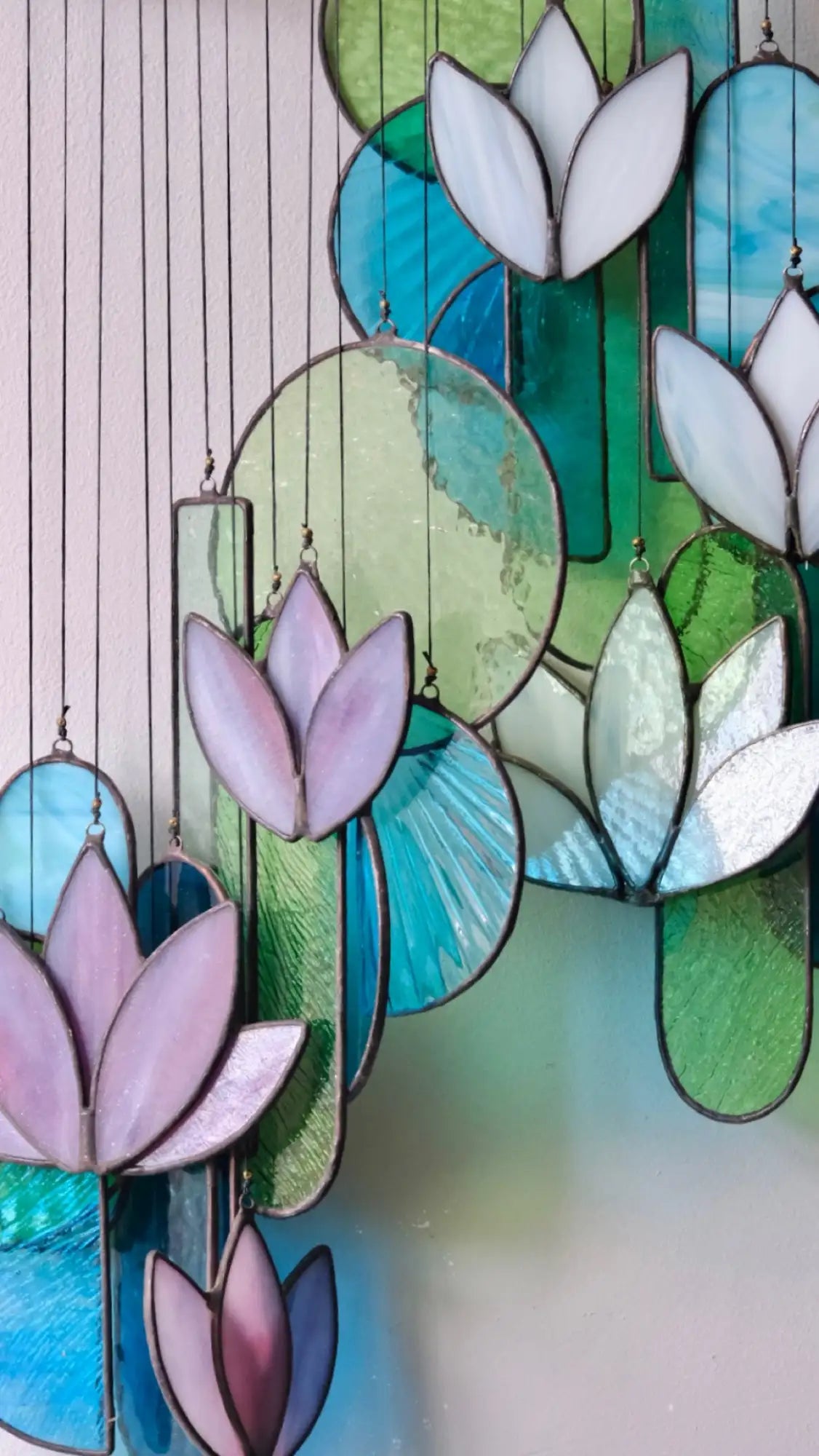 Stained glass lotus pendant decorations in pastel purple, teal, and green hues with leaded edges.
