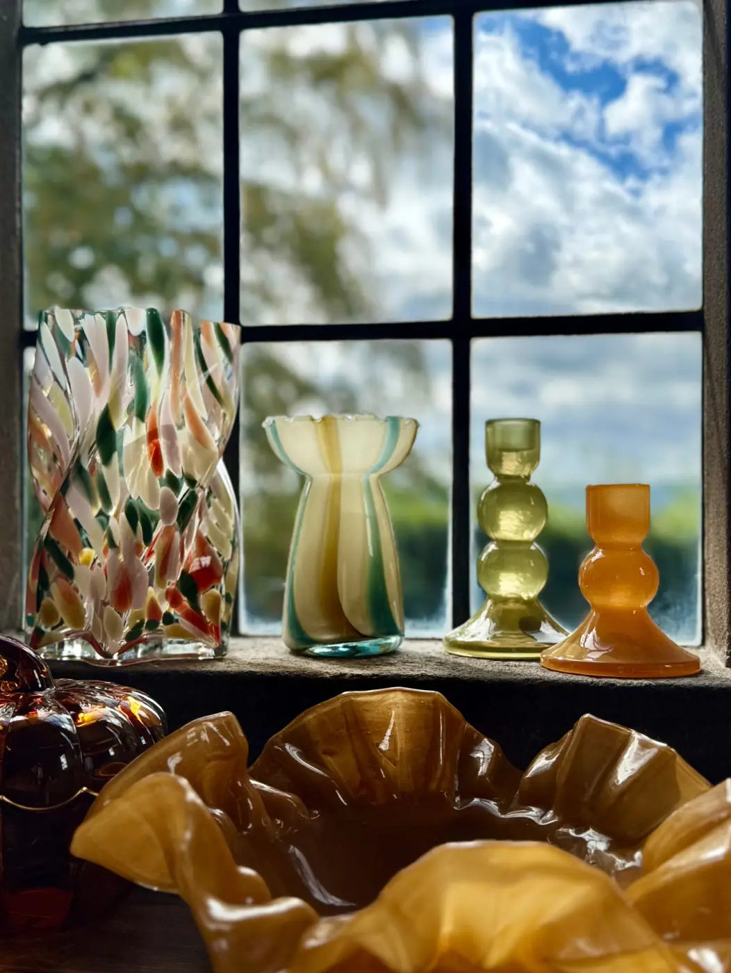 A vibrant multicolored striped glass vase with swirling green red and beige patterns ideal for home decor