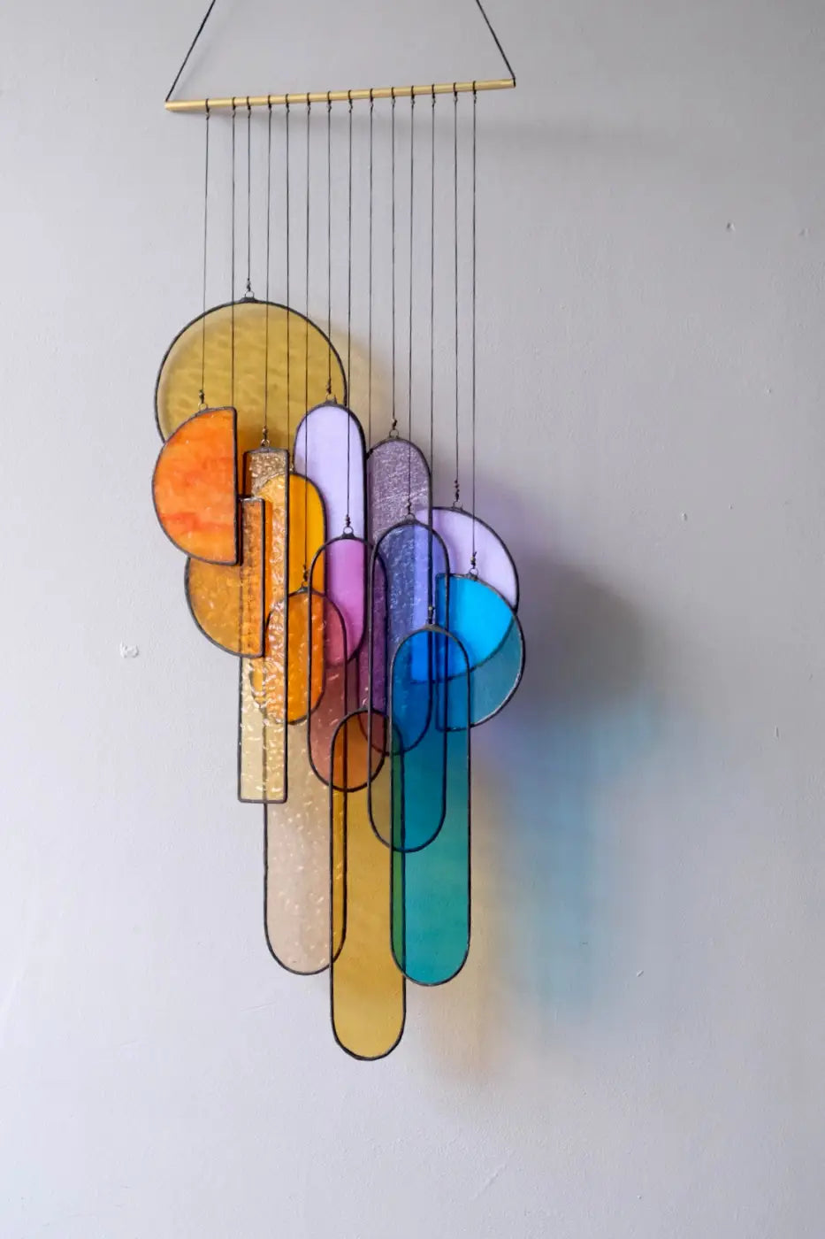 Sunset stained glass sun catcher with colorful circular and oval pieces in yellow orange purple blue and teal