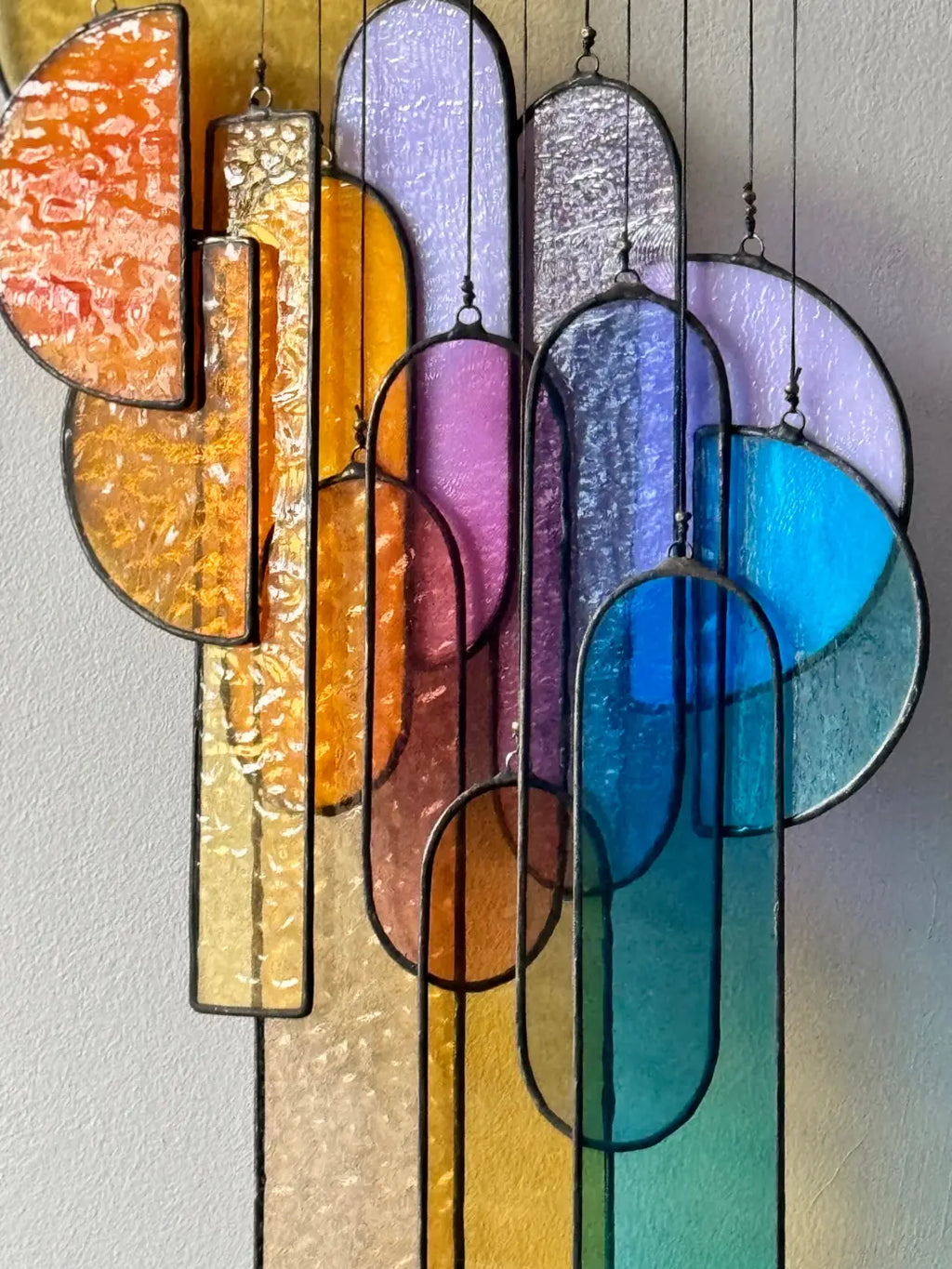 Sunset stained glass sun catcher with vibrant abstract geometric shapes in warm oranges and cool blues textured glass