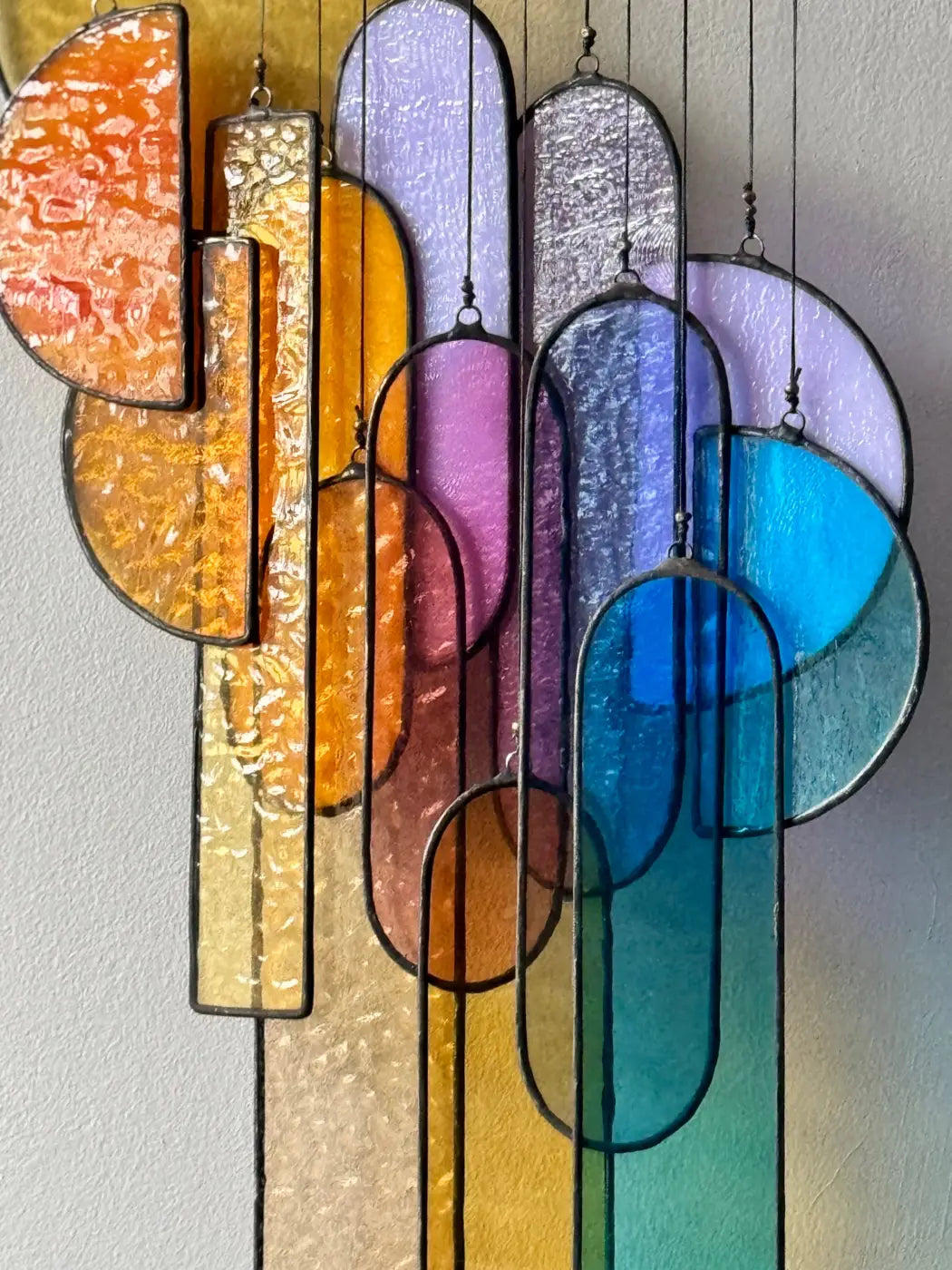 Sunset stained glass sun catcher with vibrant abstract geometric shapes in warm oranges and cool blues textured glass