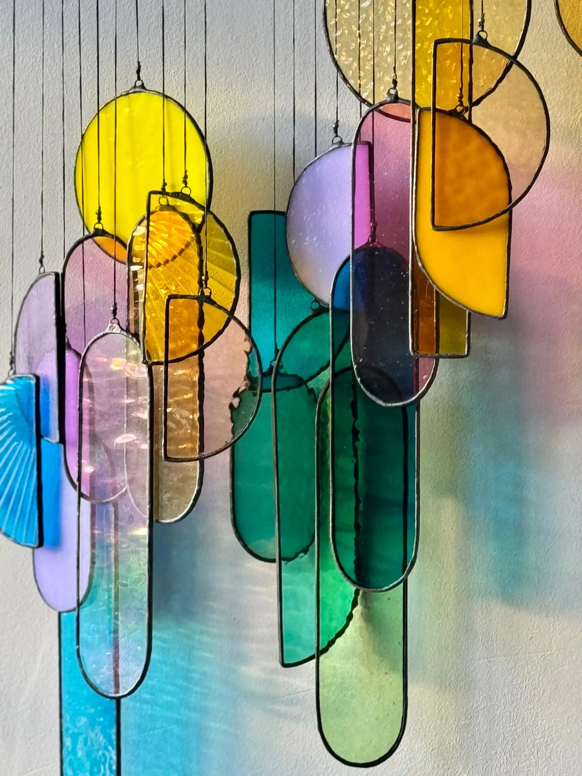 A vibrant, multi-colored stained glass chandelier with geometric shapes and black metal frames.