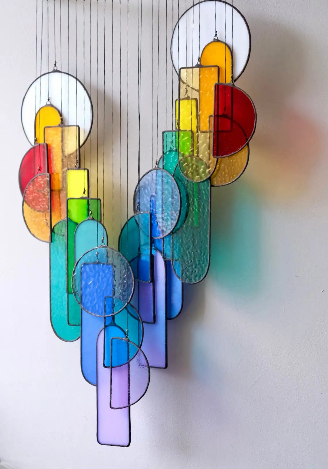 A vibrant, rainbow-colored stained glass chandelier with geometric shapes and a cascading design.