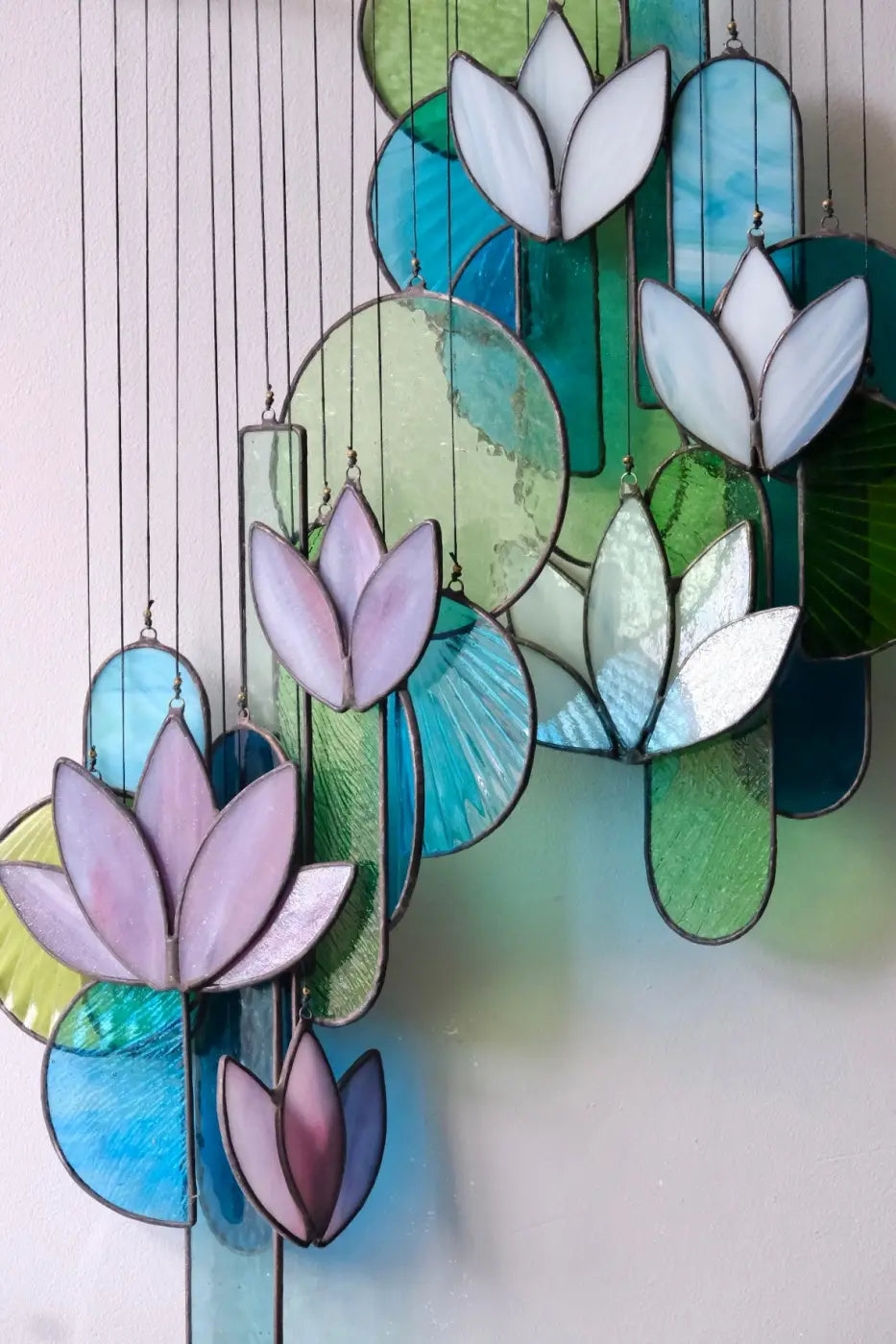 White lotus stained glass hanging art with delicate lavender and white petals and vibrant teal green and blue panels