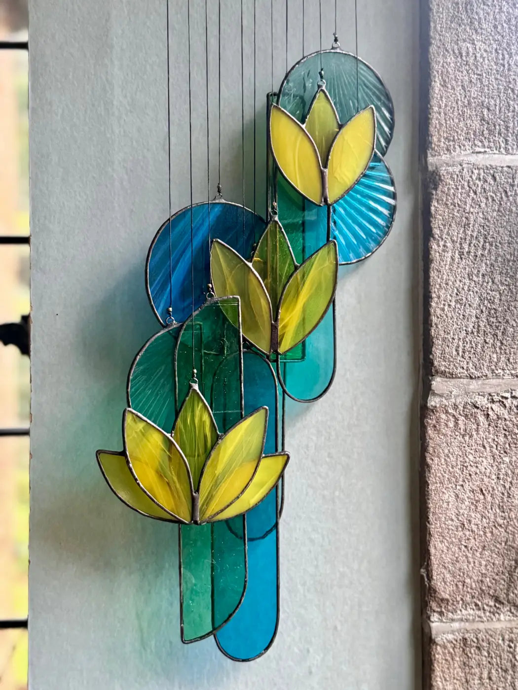 Yellow lotus stained glass hanging art with vibrant yellow lotus flowers and layered teal blue green circular panels